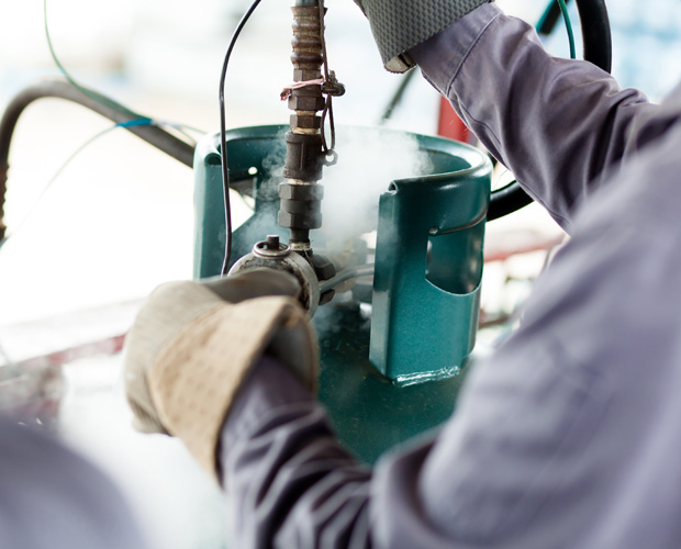Worker handling propane tank equipment.
